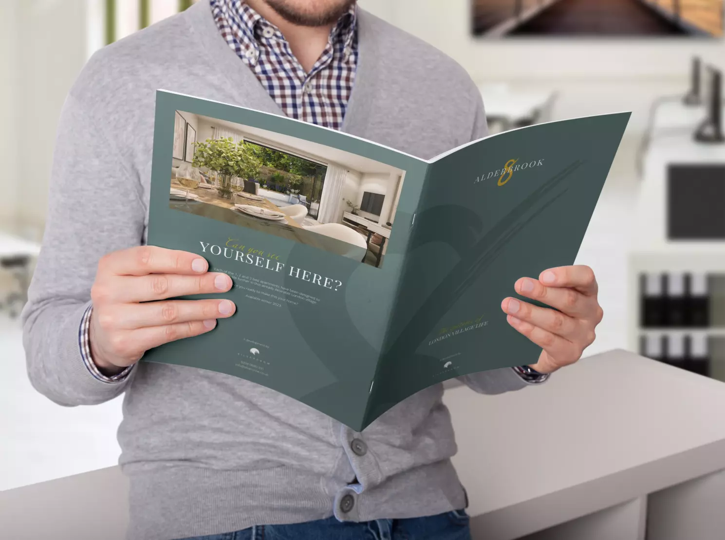 Picture of a man sitting on a desk holding the Alderbrook Road property brochure open and reading it