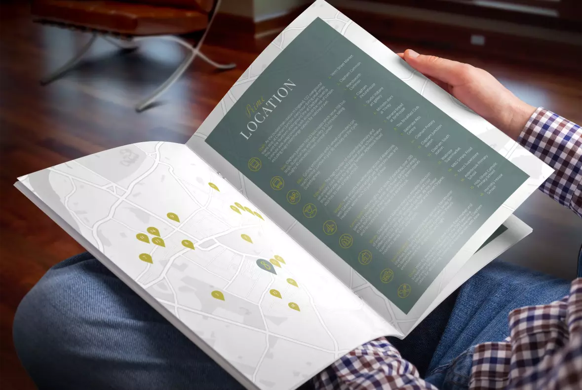 Picture of a man sitting down and holding the Alderbrook Road property brochure open and looking at the map page