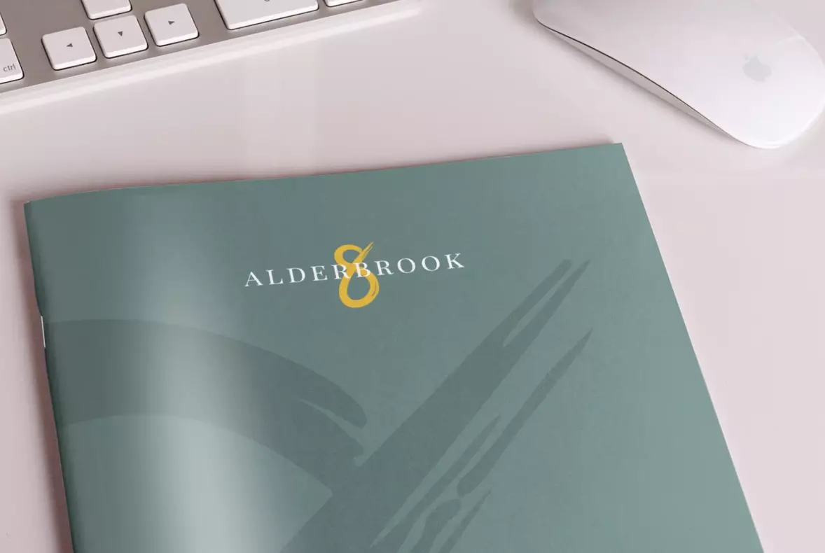 The logo for the Alderbrook Road property development shown on a mock up of a brochure sat on a desk